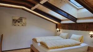 Een slaapkamer met een houten bed, dakraam en een wandlamp.