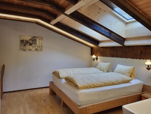 Ein Schlafzimmer mit einem hölzernen Bett, einem Oberlicht und einer an der Wand befestigten Lampe.
