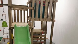 Un letto a castello con uno scivolo verde fissato al letto inferiore.