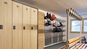 Un vestiaire avec des casiers numérotés, un porte-chaussures et un banc.