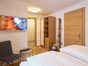 A hotel room with a bed, a chair, a TV, a wooden wardrobe, and skis. - Apartments Chesa Grischuna, (Samnaun-Dorf) by Interhome (Samnaun)