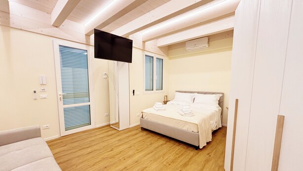 Una camera da letto con un letto, una TV montata a parete e un soffitto in legno.