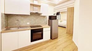 Una cucina moderna con mobili bianchi, un frigorifero in acciaio inossidabile, un forno a microonde e un forno integrato.