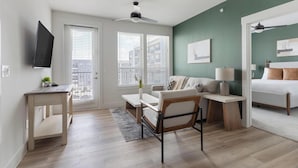 A modern apartment with a living area, a dining space, a bedroom, and a view of the city through large windows. - Landing | Modern 2BD, Clubhouse, Gym (San Antonio)