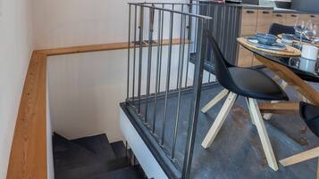 Eine moderne Küche mit Essbereich, einer Treppe mit Holzwertlauf und einem Metallgeländer.