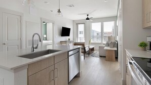 A modern kitchen with a large island, built-in appliances, and a dining area with a view. - Landing | Beautiful 2BD, Clubhouse, Gym (San Antonio)