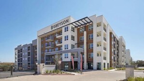 A multi-story Greyson hotel with a modern architectural design, featuring balconies and large windows. - Landing | Beautiful 2BD, Clubhouse, Gym (San Antonio)