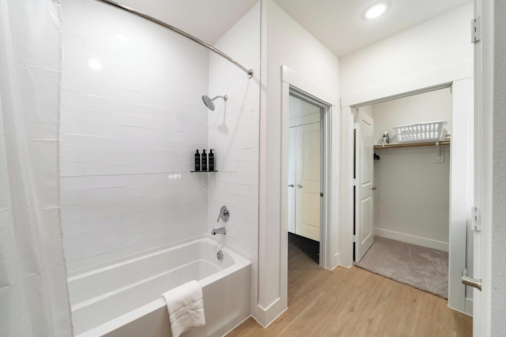 Un baño moderno con bañera, ducha y paredes cubiertas de azulejos blancos.