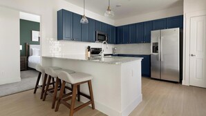 Una cocina moderna con armarios azules, un refrigerador de acero inoxidable y una encimera de granito.