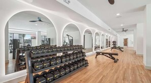 Ein Fitnessstudio mit Gewichten, Spiegeln und Trainingsgeräten.