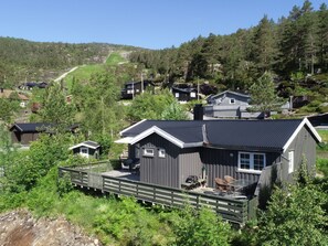A cabin with a deck, surrounded by forested hills. - Hellebu by Interhome (Eikerapen)