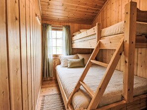 Quarto com beliche, paredes de madeira e janela com cortinas.