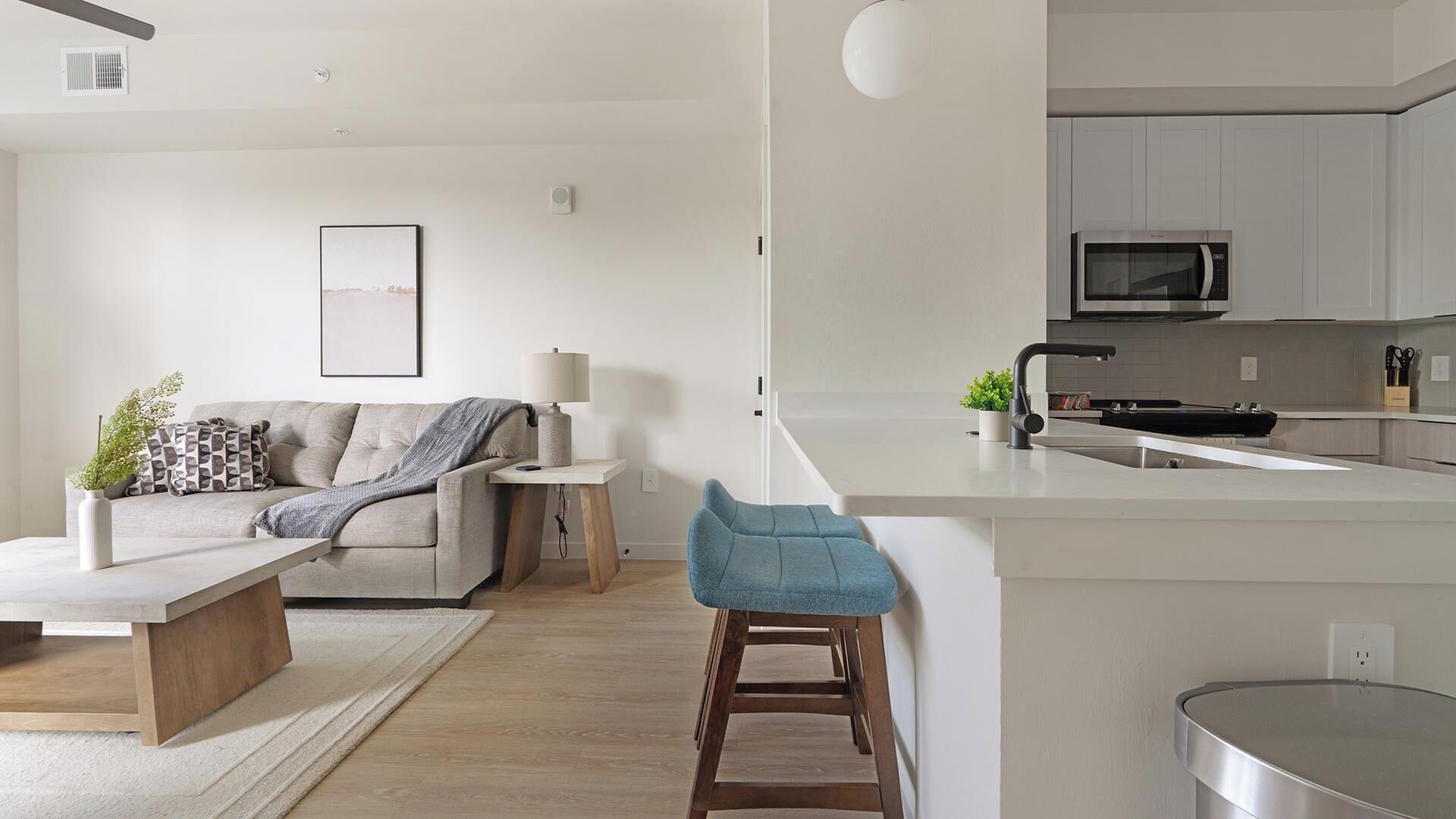 A modern kitchen with a microwave, a sink, and a bar stool.
