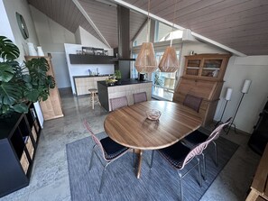 A modern kitchen with a wooden island, pendant lights, and a dining area with a round table and chairs. - Ferienwohnung Gassmann Appartement/Fewo 4-Bett Wohnung mit Dusche, Bad u. Balkon by Interhome (Spiez)