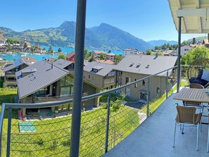 A balcony with a view of a mountain, a lake, and a row of houses. - Ferienwohnung Gassmann Appartement/Fewo 4-Bett Wohnung mit Dusche, Bad u. Balkon by Interhome (Spiez)