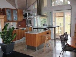 Une cuisine moderne avec des meubles en bois, un îlot central et un coin repas équipé d’une chaise.