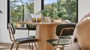 Een eetruimte met een houten tafel, stoelen en een potplant.