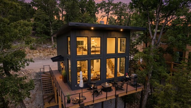Een moderne chalet met terras, meerdere ramen en een trap naar de ingang.