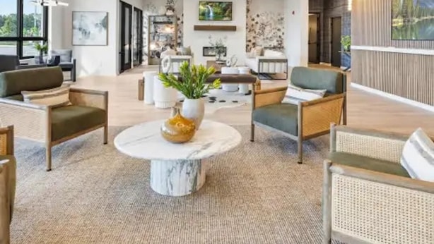 Een modern interieur met een ronde lamp, een centrale ronde tafel en zithoekjes.