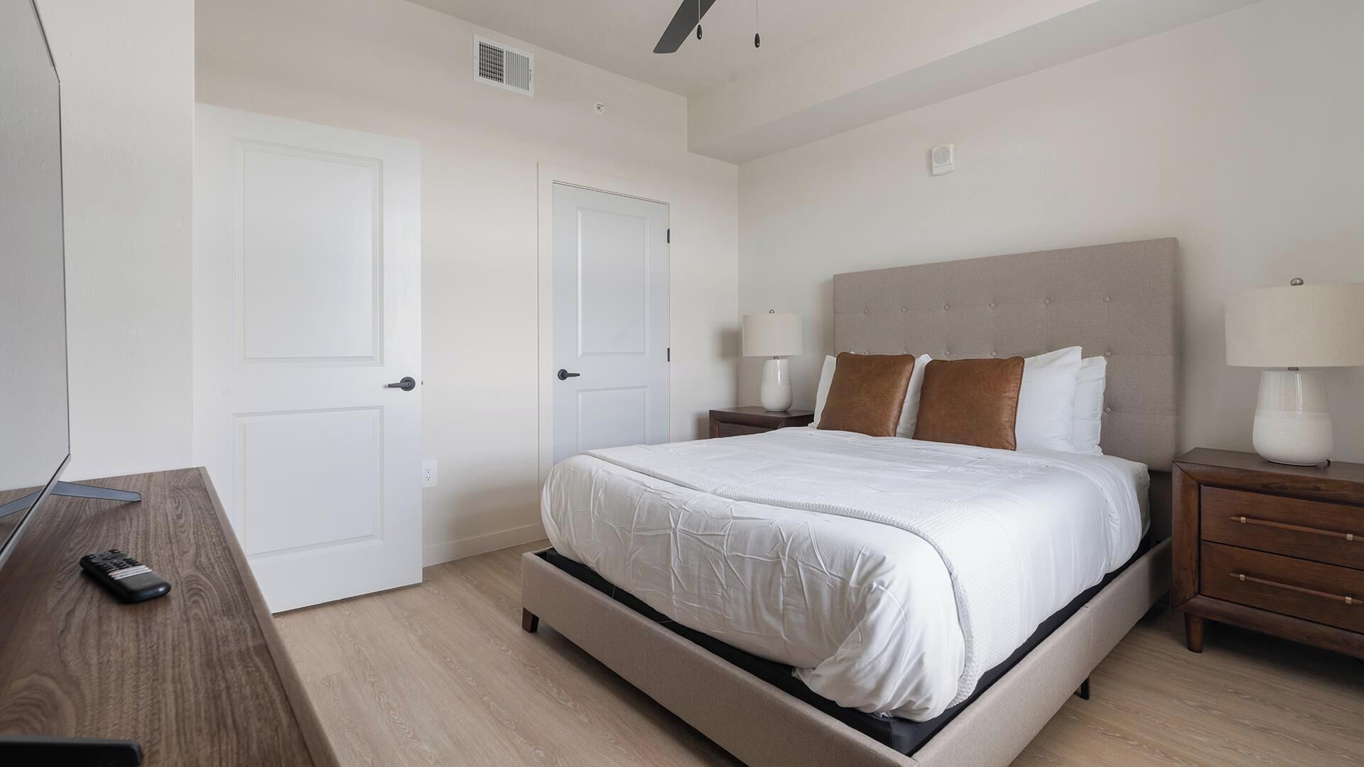 Un dormitorio con cama, mesitas de noche, un escritorio y un televisor.