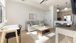 Ein modernes Wohnzimmer mit einer Couch, einem Couchtisch und einem Essbereich mit Tisch und Stühlen.