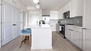 Una cocina moderna con armarios blancos, una isla central, un microondas y una cafetera.