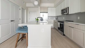 Une cuisine moderne avec des meubles blancs, un îlot central, un four à micro-ondes et une cuisinière.