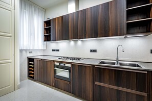 A modern kitchen with dark wood cabinets, a stainless steel sink, and a built-in oven. - Frescoed apartment in the heart of Florence (Firenze)