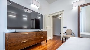 Ein modernes Schlafzimmer mit einem Holzkapuzenpaneel, einem großen Spiegel, einem Bett und einem Sessel.