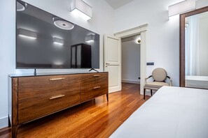 A modern bedroom with a wooden dresser, a large mirror, a bed, and a chair. - Frescoed apartment in the heart of Florence (Firenze)