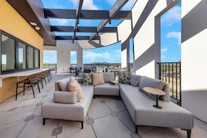 A modern outdoor patio with a sectional sofa, a dining table, and chairs. - Landing | Spectacular 1BD, Pool, Game Room (Largo)