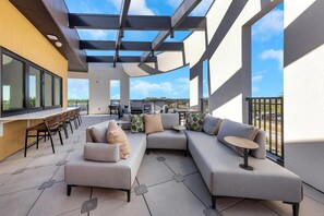 A modern outdoor patio with a sectional sofa, a dining table, and chairs. - Landing | Stylish 1BD, Pool, Game Room (Largo)