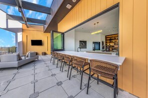 Ein moderner Außenbereich mit einer langen Bar, Korbstühlen und einer Couch.