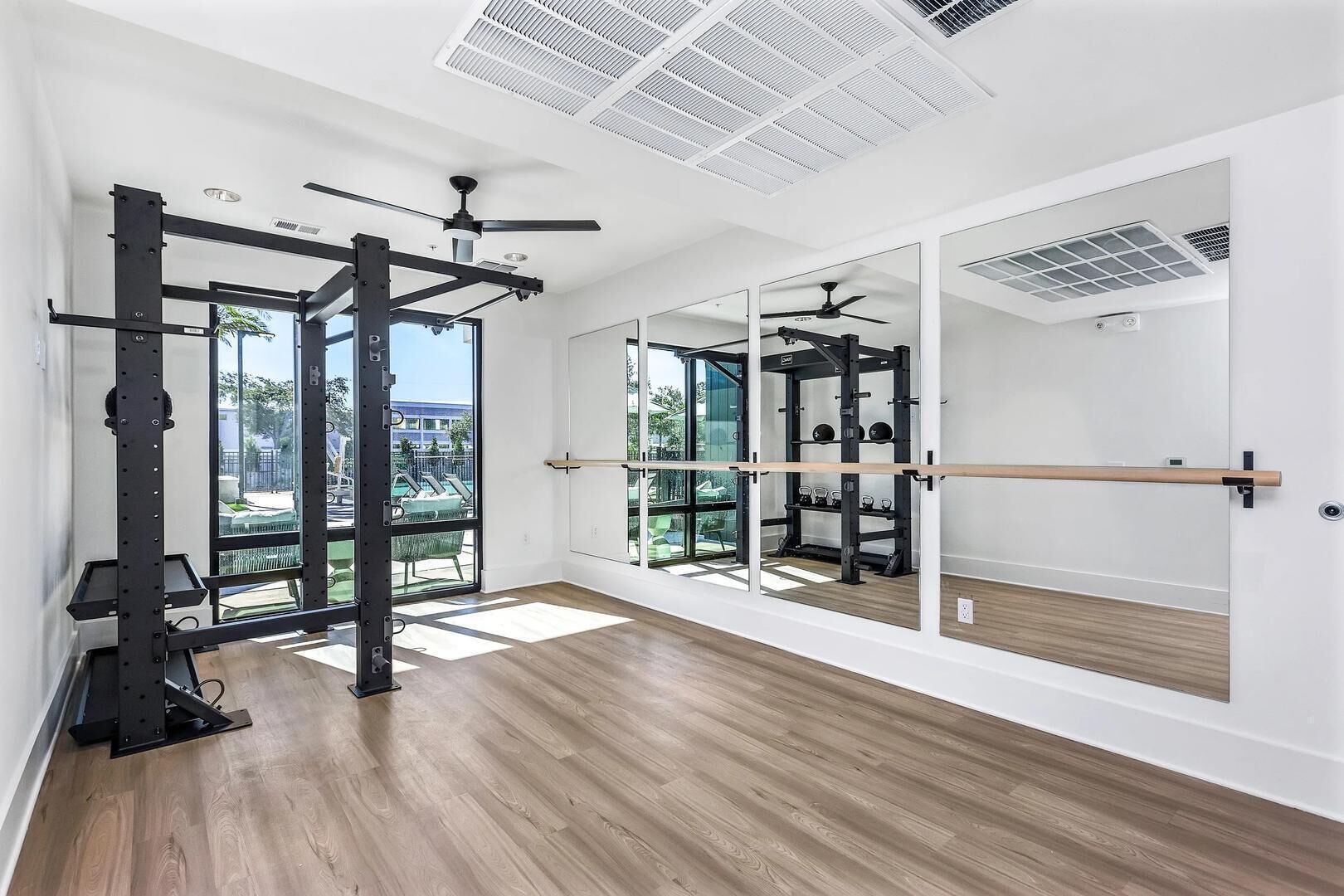 Una habitación amplia con un espejo grande, ventilador de techo y vistas al exterior.