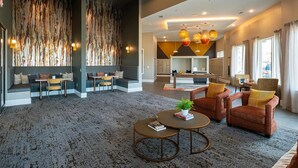 A spacious lobby with seating areas, a reception desk, and a large abstract wall. - Landing | Chic 1BD, Game Room, Gym (Richmond)