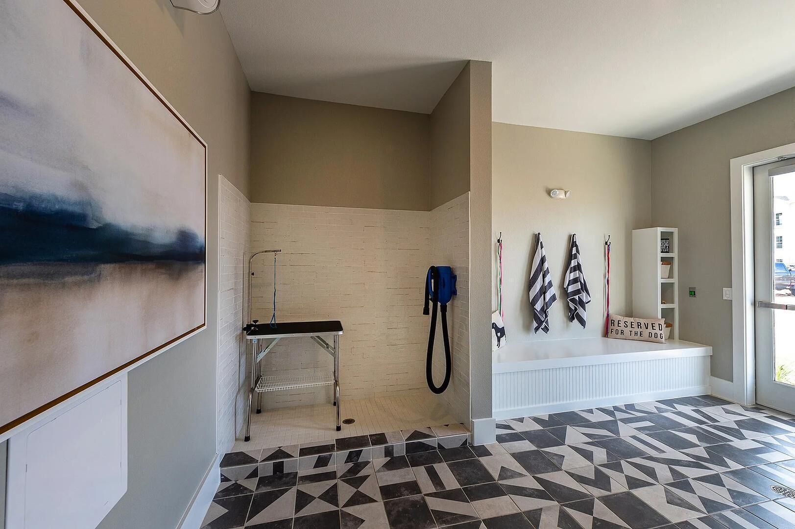 A hallway with a shower, a bench, and a wall with towels and a sign.