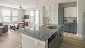 A modern kitchen with granite countertops, stainless steel appliances, and a dishwasher. - Landing | Amazing 2BD, Game Room, Gym (Richmond)