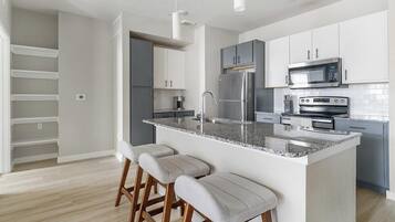 A modern kitchen with a granite countertop, stainless steel appliances, and a built-in island with bar stools.