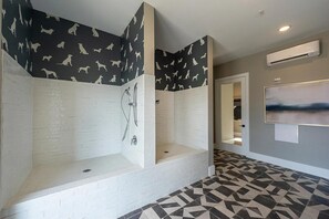 Une salle de bain moderne avec une douche, des murs en briques blanches et un sol carrelé à motifs géométriques.