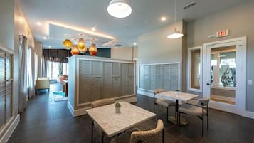 Un hall d’hôtel comprenant des casiers, un comptoir de réception et un espace détente avec des tables et des chaises.