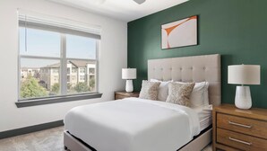 A bedroom with a large bed, two bedside tables with lamps, a window with blinds, and a green accent wall. - Landing | Spectacular 1BD, Gym (Terrell)