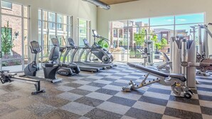 Un gimnasio con cintas de correr, elípticas y equipos de pesas.