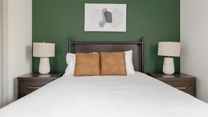 A hotel room with a large bed, two bedside tables with lamps, a green wall, and a piece of abstract art above the bed. - Landing | Spectacular 1BD, Gym, Clubhouse (Leander)