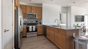 Eine moderne Küche mit Holzschränken, Edelstahlgeräten und einer Granitarbeitsplatte.
