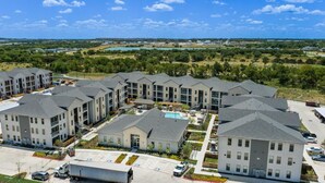 A modern apartment complex with multiple buildings, a swimming pool, and a parking area. - Landing | Incredible 1BD, Clubhouse, Gym (Leander)