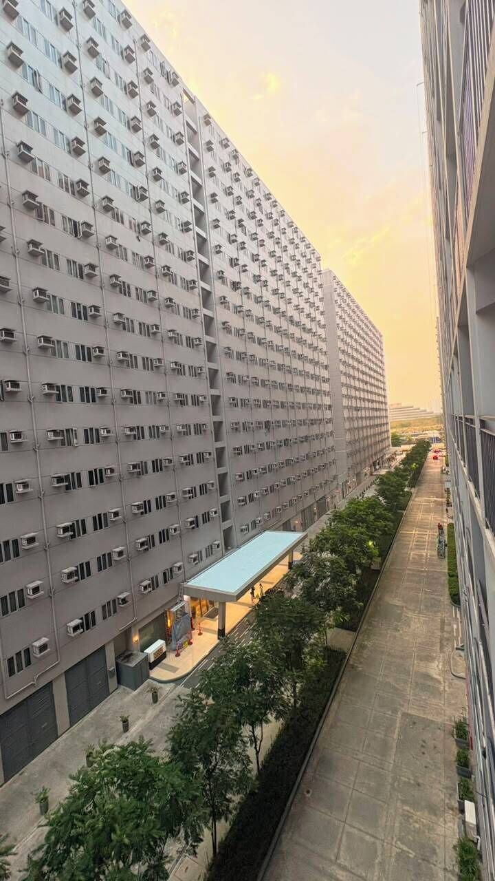 Un immeuble résidentiel de grande hauteur, doté de nombreux balcons, d’une galerie couverte et offrant une vue sur un ciel dégagé.