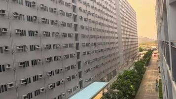 Un immeuble résidentiel de grande hauteur, doté de nombreux balcons, d’une galerie couverte et offrant une vue sur un ciel dégagé.
