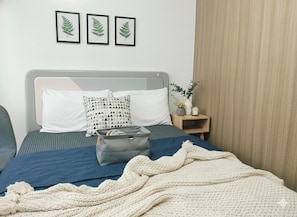 A neatly made bed with a blue and white striped bedspread, a grey headboard, and a grey storage basket. There are three framed leaves on the wall above the bed. - Mall of Asia - Asian Budget Stays (Pasay City)
