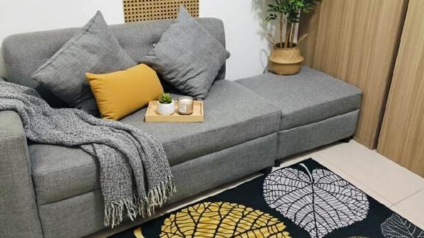 A grey sofa with cushions, a small plant, and a tray with candles and a plant. - Mall of Asia - Asian Budget Stays (Pasay City)