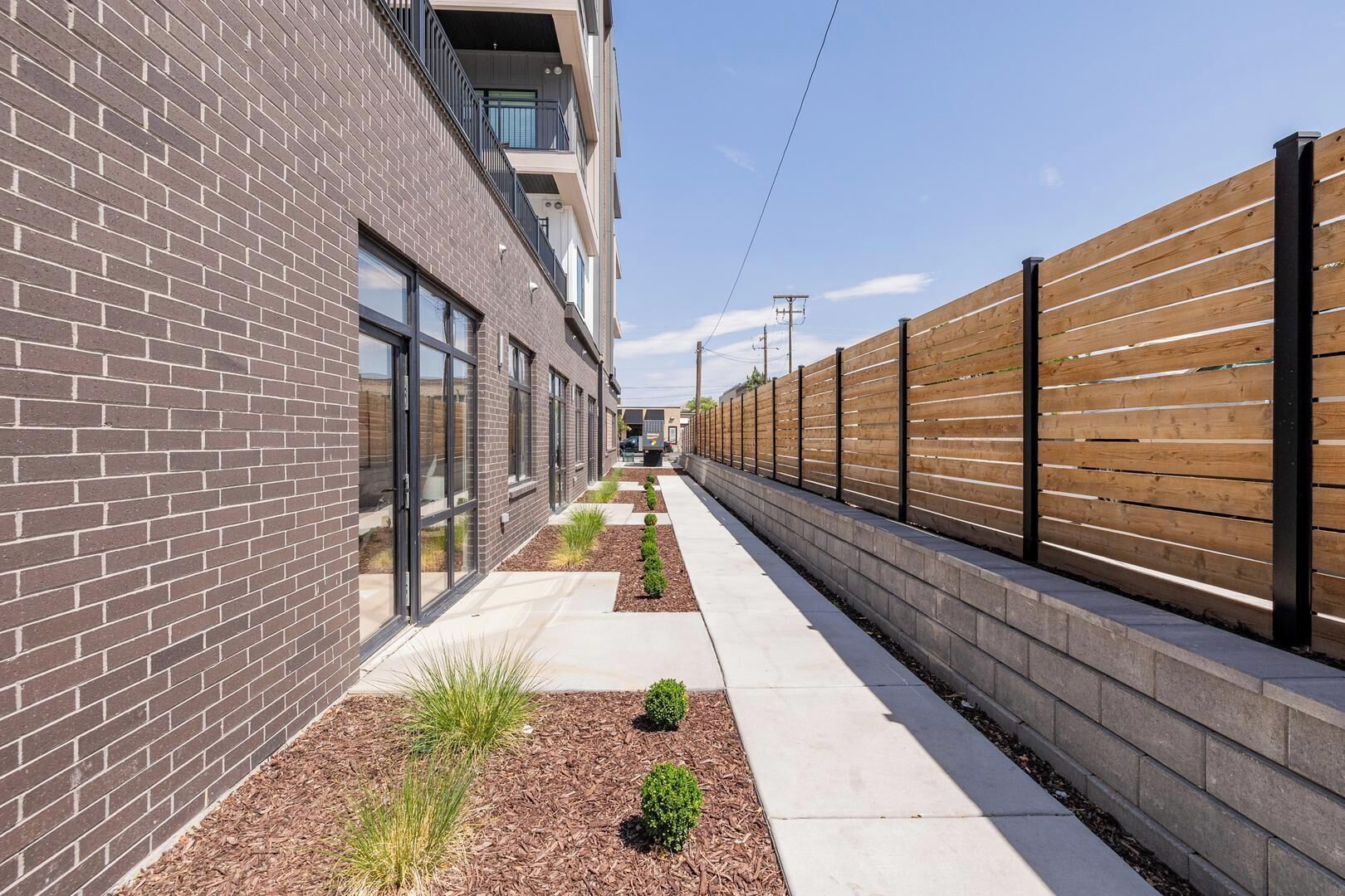 Un bâtiment moderne avec une façade en briques, de grandes fenêtres et une clôture en bois.